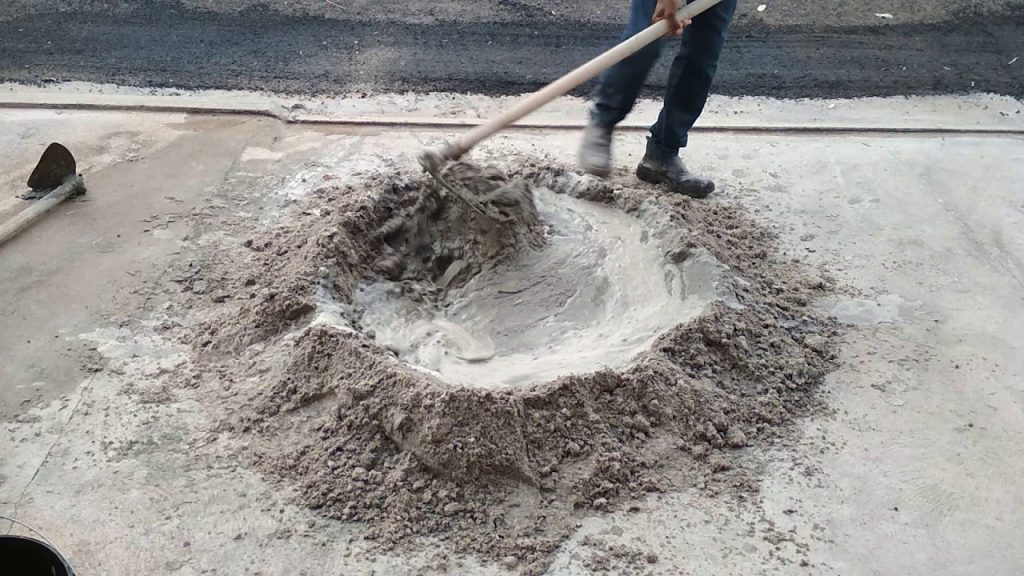 Operário preparando a argamassa para assentar blocos com uma enxada